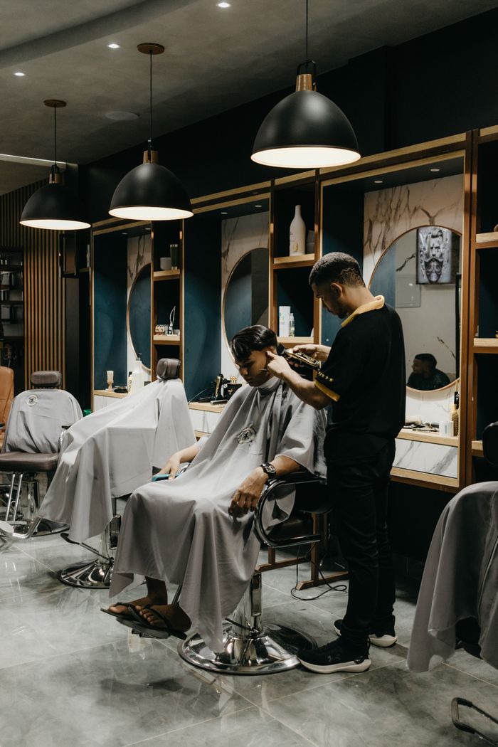 services-02 A professional barber giving a haircut to a client inside a stylish barbershop.