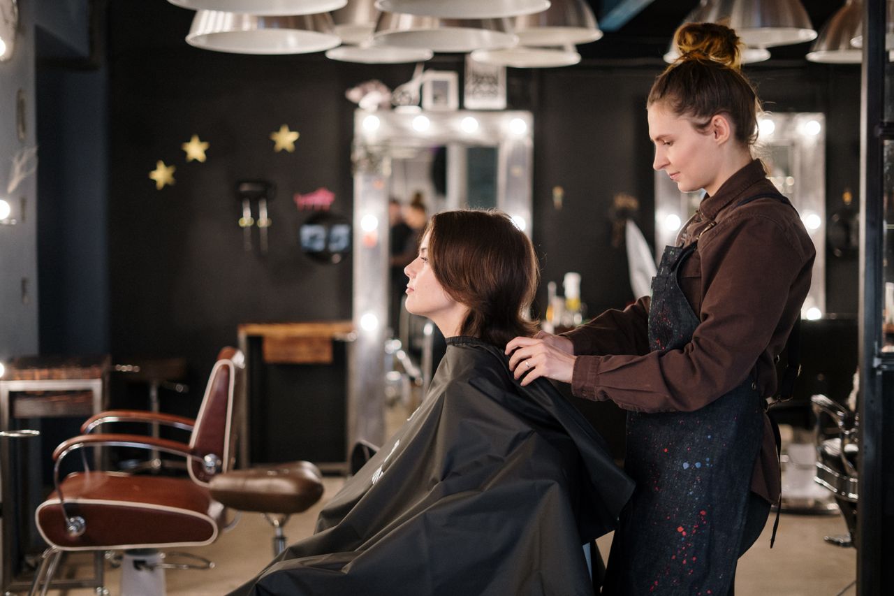 services-03 A hairstylist trims a client's hair in a modern salon setting, capturing a moment of focus.