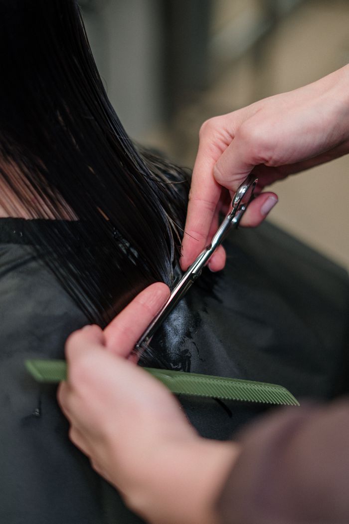 about-07 Close-up of a hairdresser cutting black hair in a salon, focusing on precision and style.
